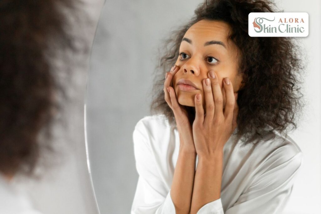 Woman checking her under-eye area in the mirror, looking at dark circles